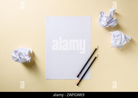 Blank writing sheet with pen and crumpled paper balls lay flat on yellow background Stock Photo