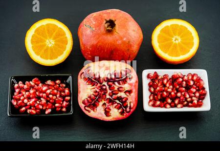 pomegranate, anar (Punica granatum), Pomegranates, one halved, pomegranate seeds in a bowl, served with orange slices Stock Photo