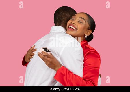 Black woman joyfully hugging man after proposal, ring shown Stock Photo