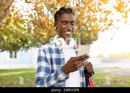 Content young african american man with headphones checks smartphone outdoors Stock Photo
