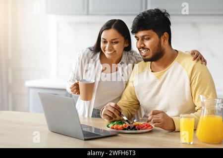 Happy young indian family using laptop while have breakfast Stock Photo