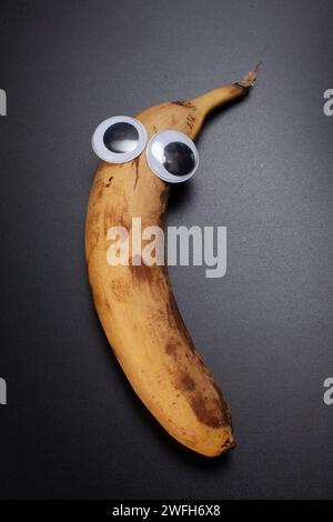banana with eyes isolated on black background Stock Photo