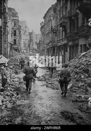 American troops patrolling the ruins of Bonn, in the German state of North Rhine-Westphalia, located on the banks of the Rhine. It was taken by the Allies on the 9th March 1945 as the Second World War gradually came to an end. Stock Photo