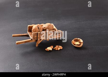 Walnut in a antique barrow and in shopping carts on dark background. Stock Photo