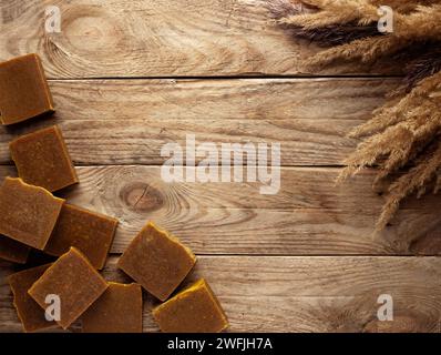 Bars of natural soap with dried flowers on a wooden table. Stock Photo