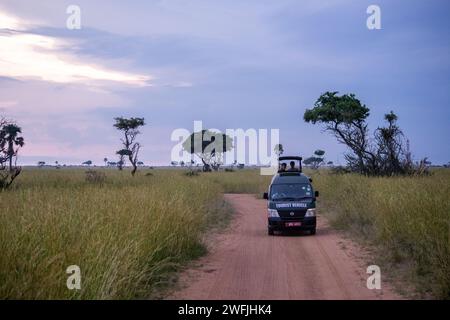 A safari vehicle driving down a dirt road in the African Savana - Murchison Falls National Park, Uganda Stock Photo