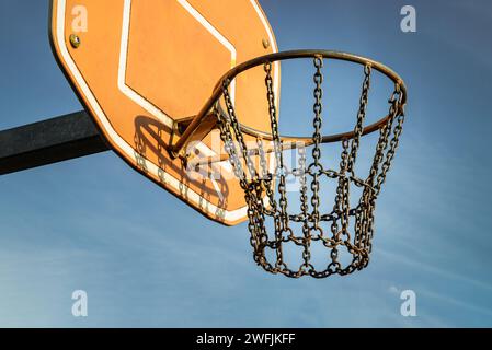 Edinburgh, Scotland, Jan 19, 2024 - Side view of Basketball backboard with the hoop metal ring and steel chain net against blue sky background seen fr Stock Photo