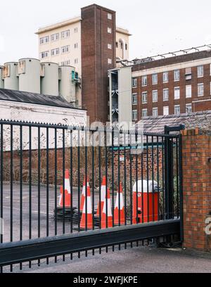 metal gates at the factory entrance closed with a pile of traffic cones Stock Photo
