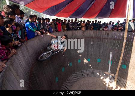 Dhaka, Khulna, Bangladesh. 31st Jan, 2024. Daring motorists entertain spectators by dangerously driving motorcycles on a vertical ''wall of death'' in Khulna, Bangladesh. Performers travel without protective gears at speeds of up to 80 km/h so that their vehicles can balance on the 25-foot-high wooden plank. Riders pull off death-defying stunts to wow bystanders in an attempt to make extra money as they ride vertically up the side of a wall. They perform to entertain those who have paid an entry fee of 20 pence for the entertainment. (Credit Image: © Joy Saha/ZUMA Press Wire) EDITORIAL USAGE Stock Photo