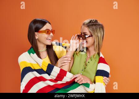 joyous adorable teenage girls with sunglasses hugging and covering with blanket, friendship day Stock Photo