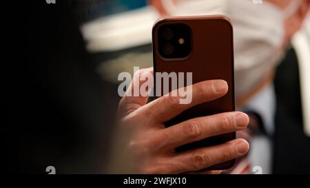 Amidst the hustle of a Japanese subway station, a man in business absorbed in his phone, merging the worlds of transportation and technology. Stock Photo