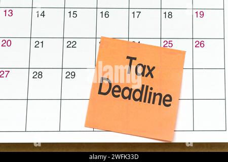 Tax deadline text on orange paper sticky note and stuck to a calendar background. Tax season concept. Stock Photo