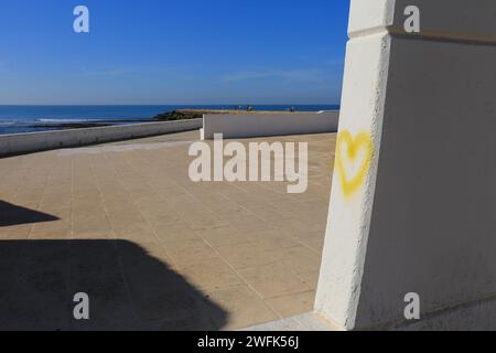 Yellow heart drawn on wall on Playa de la Costilla beach and promenade in Rota city, Cadiz, on a sunny day Stock Photo