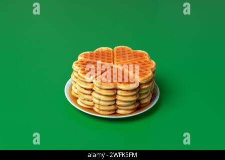 Stack of homemade waffles on a plate with mapple syrupe powred over, minimalist on a green table Stock Photo