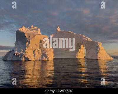 A huge high breakaway glacier drifts in the southern ocean off the coast of Antarctica at sunset, the Antarctic Peninsula, the Southern Arctic Circle Stock Photo