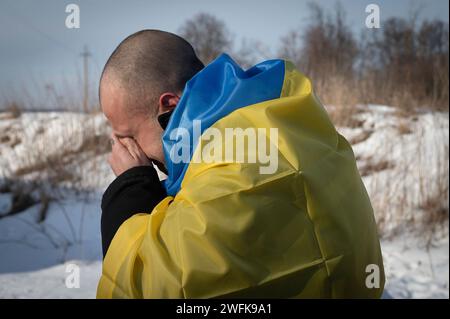 Bakhmut, Ukraine. 31st Jan, 2024. A Ukrainian soldier weeps into a Ukraine flag after arriving back home following a POW exchange between Russia and Ukraine, January 31, 2024 in an undisclosed location. The exchange was the 50th return of prisoners of war and involved 207 Ukrainian defenders. Credit: Pool Photo/Ukrainian Presidential Press Office/Alamy Live News Stock Photo