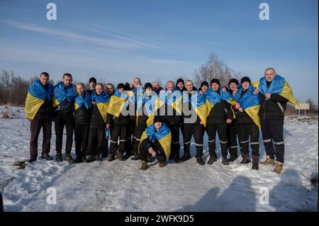 Bakhmut, Ukraine. 31st Jan, 2024. Ukrainian soldiers pose together with flags after arriving back home following a POW exchange between Russia and Ukraine, January 31, 2024 in an undisclosed location. The exchange was the 50th return of prisoners of war and involved 207 Ukrainian defenders. Credit: Pool Photo/Ukrainian Presidential Press Office/Alamy Live News Stock Photo