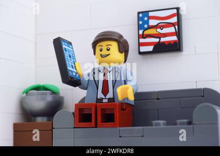 Tambov, Russian Federation - January 30, 2024 A Lego businessman minifigure sitting on a couch and answering the cellphone. Stock Photo