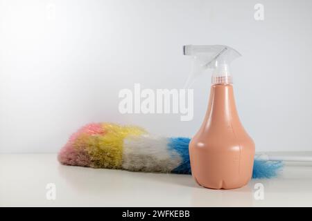Spray bottle and colorful dust sweeper lying on a shelf. Stock Photo