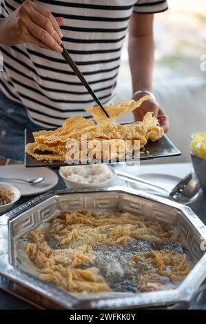 Female person has a hot meal with lots of ingredients to cook in a hot pot style boiling soup. This traditional Asian dish she prepares with fried tof Stock Photo