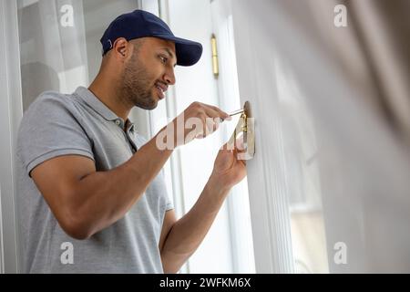 Bearded man repairing window handle at home. Stock Photo