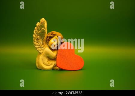A little angel and a hearth on green background. Valentines Day, 14 th. february concept. Christmas angel ornaments. Angel and love concept. Stock Photo
