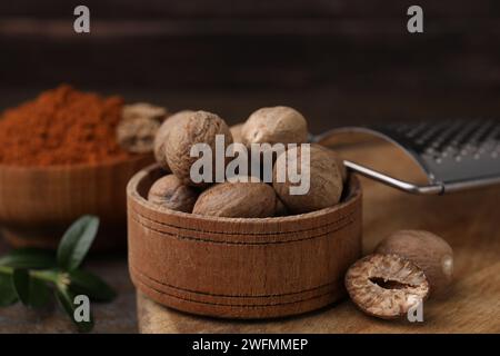 Nutmegs in wooden bowl and grater on table Stock Photo