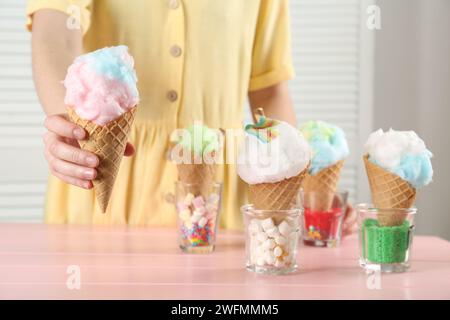 Woman holding waffle cone with cotton candy indoors, closeup Stock Photo