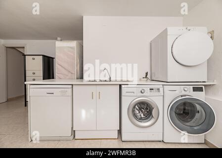Laundry room on the ground floor of a single-family home with white furniture and appliances Stock Photo