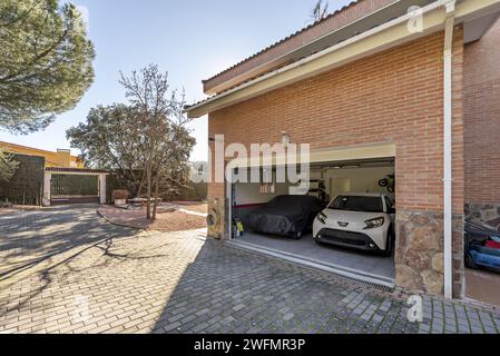 Garage with capacity for two vehicles of a single-family house with a metal fence and a perimeter surrounded by hedges Stock Photo