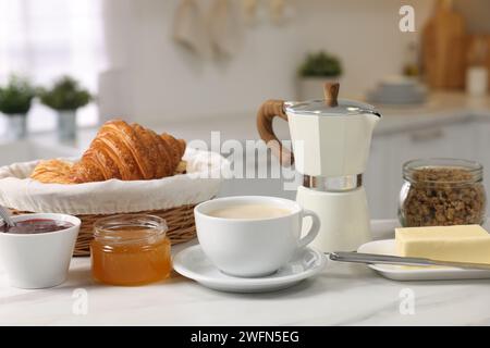 Breakfast served in kitchen. Fresh coffee, granola, croissants, jam, butter and honey on white table Stock Photo