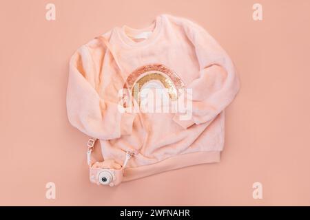 Children's pink sweater and digital camera on a pink background Stock Photo