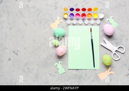 Blank card with paints, Easter eggs and paper rabbits on grunge background Stock Photo