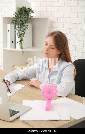 Beautiful young woman with handheld mini fan at home Stock Photo - Alamy