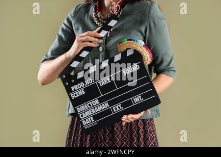 Beautiful woman with movie clapper and sombrero hat on green background Stock Photo