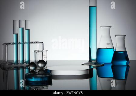 Blue liquid is filled inside petri dish and some laboratory glassware, decorated with glass balls and round podium. Blank space to display product Stock Photo