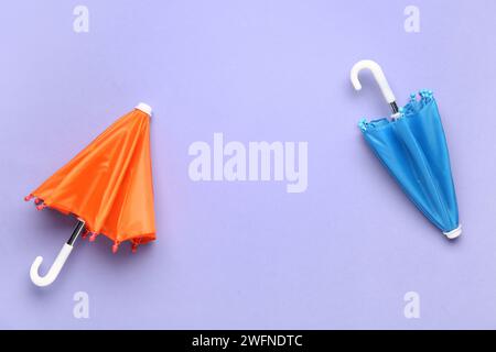 Mini stylish umbrellas on lilac background Stock Photo