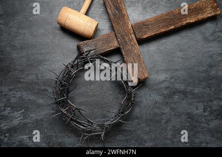 Wooden cross with crown of thorns and hammer on grey grunge background Stock Photo