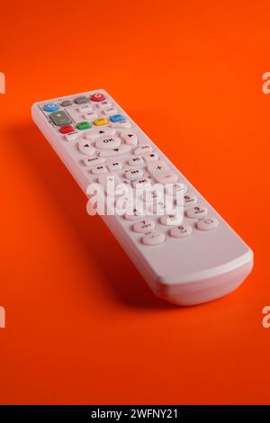 a TV remote with various function buttons on a lit background Stock Photo