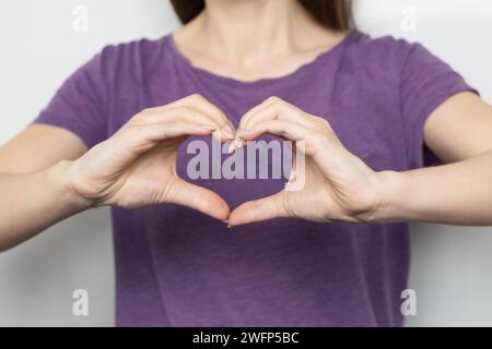 Inspire inclusion. Zoomers symbolize love. Faceless woman finger heart dressed purple t-shirt. Hand showing heart. International Women's Day 2024 Stock Photo