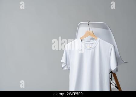 White blank t-shirt hanging on chair in empty room Stock Photo