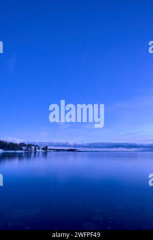 A beautiful lake surrounded by distant trees under a starry night sky ...