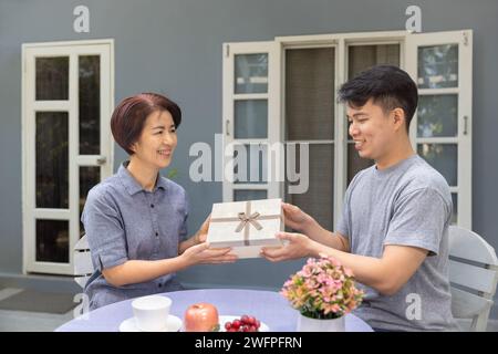 Adult son gives a gift to mom on the mother's day. Stock Photo