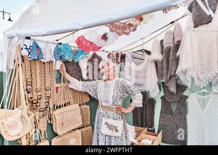 Senior white woman, selling warm knitted items and crochet accessories at Irbit fair, Russia Stock Photo