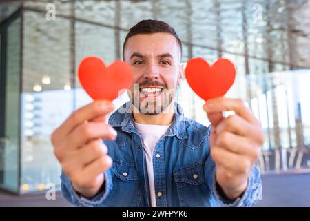 portrait smiling young woman holding hearts on Valentine's Day outdoors. Stock Photo