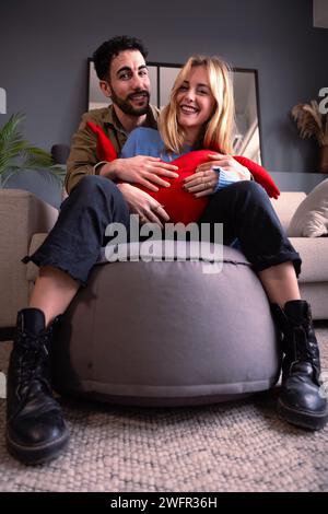 Vertical close-up Young couple smiling and hugging a heart looking at camera Stock Photo