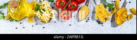 Various dried  spaghetti, noodles, pasta  set in spoons on white table background. Different shapes types raw italian pasta with herbs, olive oil, tom Stock Photo