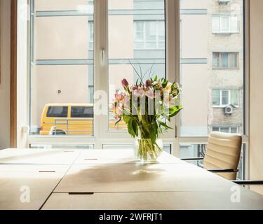 Empty room with table near the window and few chairs near that. Sunlight coming from behind. Flowers in a vase on the table. Stock Photo