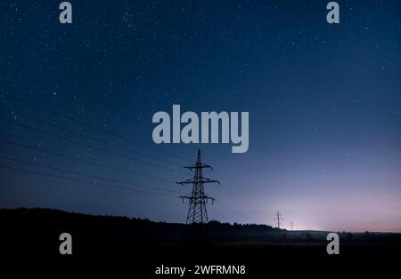 Electricity transmission towers with glowing wires against the starry sky. Stock Photo