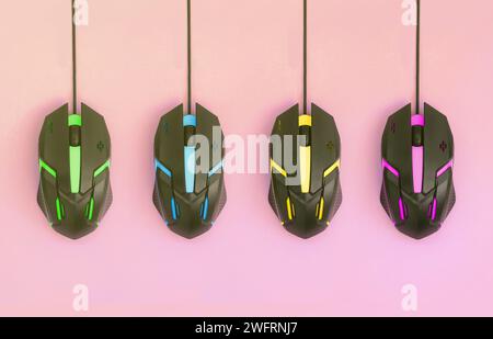 Several computer mice hang on a pastel pink background. The concept of cooperative computer video games, the use of auto-clicker and pay-per-click platforms. Flat lay abstract minimal composition Stock Photo